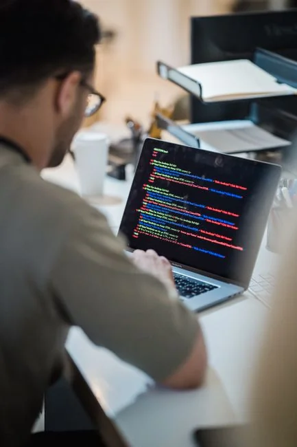 Muškarac radi na web dizajnu u kućnom uredu s dva monitora.