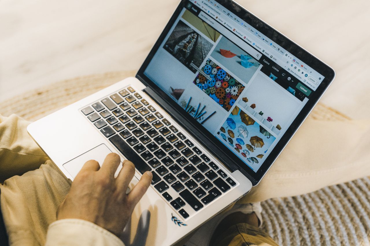 Osoba koja koristi laptop za pregledavanje stock photo web stranica. Freelancing rad u ugodnom okruženju.